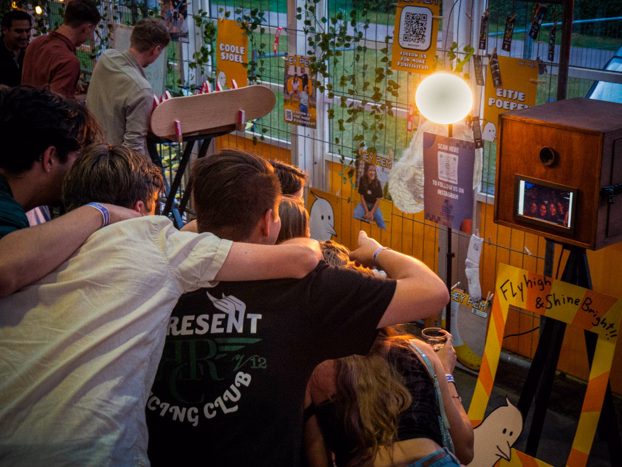 Een groep gasten met de armen om elkaar heen kijkt naar zichzelf op het scherm van de photobooth.