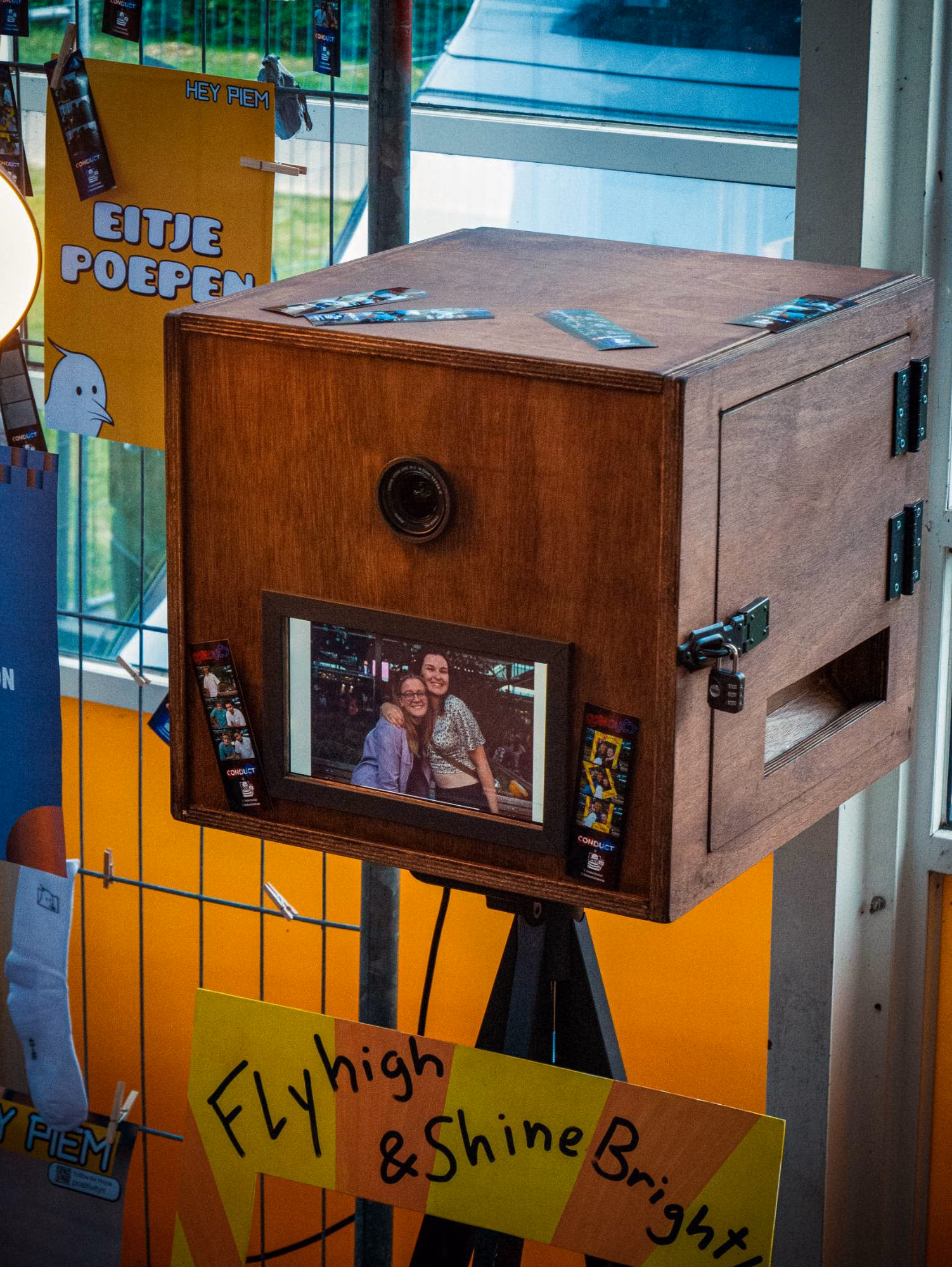 Voorkant van de houten photobooth: de camera bovenin en op het scherm het resultaat van twee lachende gasten.